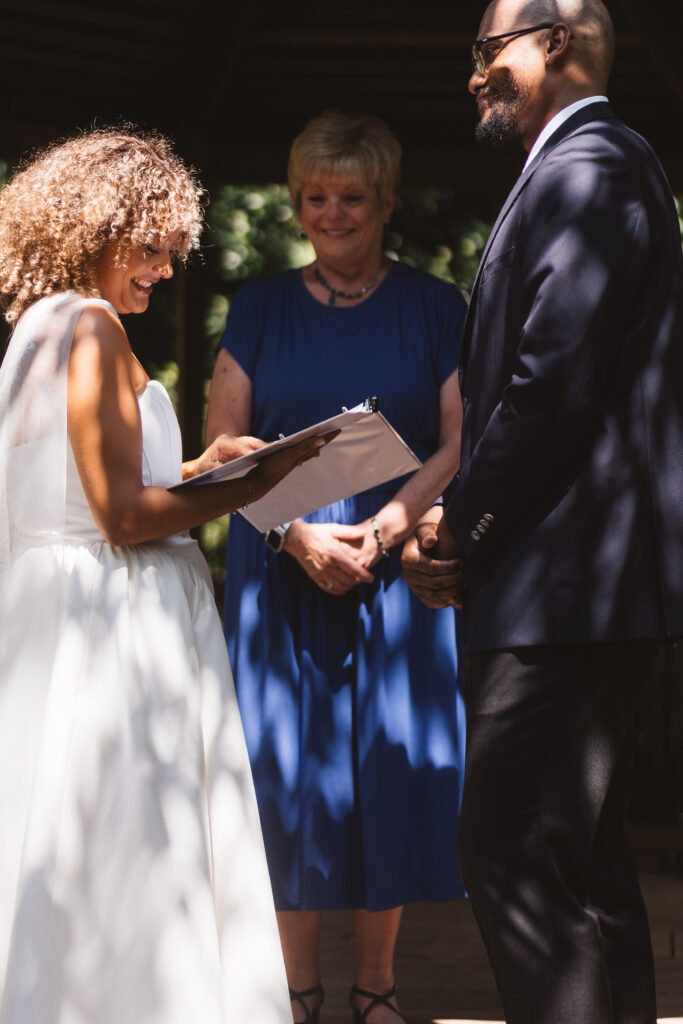 Bride reads her vows with a smile on her face while the groom holds back emotion, photographed by Philadelphia and New Jersey based travel wedding photographer, Madison Neumann Photography.