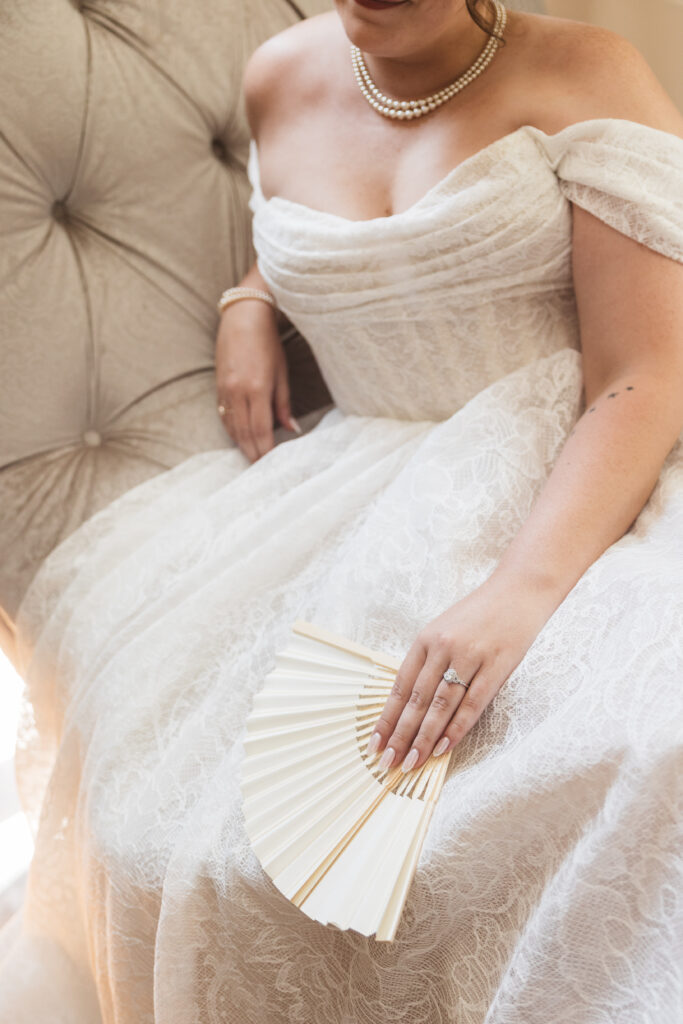 Detail photo of bride on chaise lounge holding her fan with her engagement hand, photographed by Philadelphia and New Jersey based travel wedding photographer, Madison Neumann Photography.