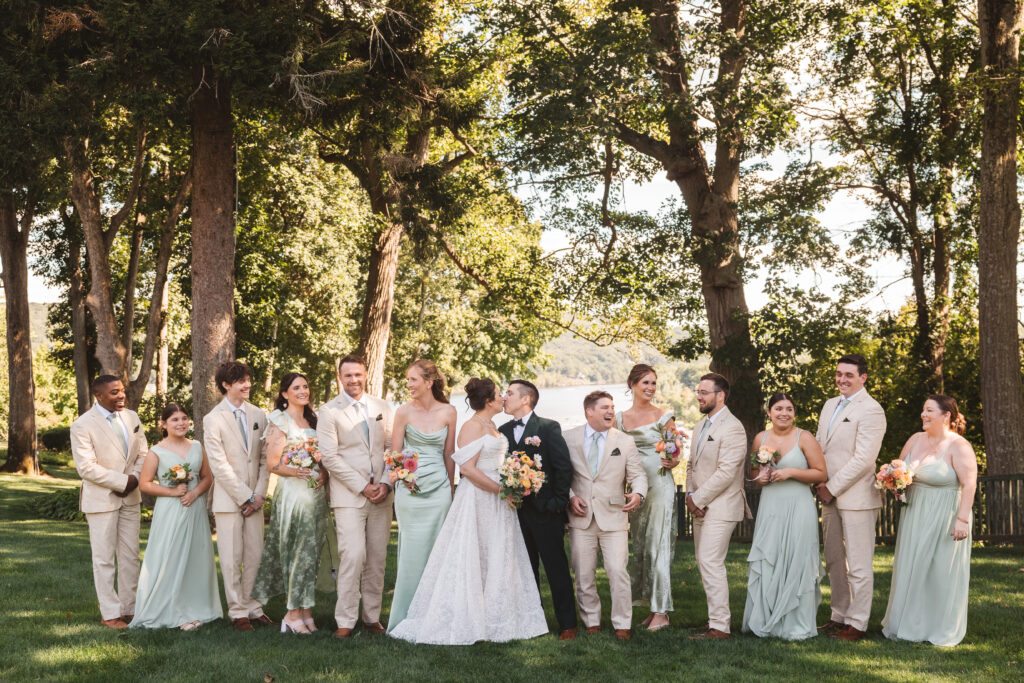 Bride and groom share a kiss as they pose with the entire wedding party at St. Clements Castle, photographed by Philadelphia and New Jersey based travel wedding photographer, Madison Neumann Photography.