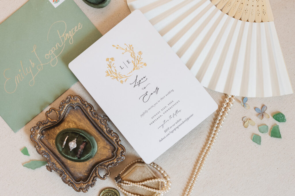 Flat lay of wedding invitation with wedding details such as a fan, jewelry, and the wedding rings, photographed by Philadelphia and New Jersey based travel wedding photographer, Madison Neumann Photography.