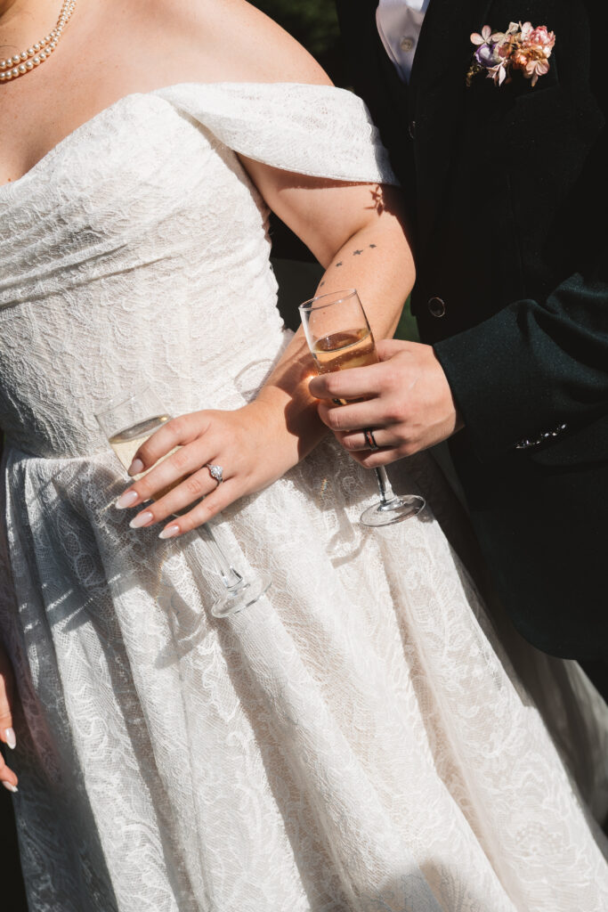Beautiful detail shot of bride and groom holding their champagne with focus on their rings and outfits, photographed by Philadelphia and New Jersey based travel wedding photographer, Madison Neumann Photography.