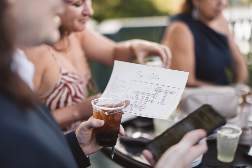 Guests enjoy cocktail hour with games and drinks such as a crossword puzzle called 'Sip and Solve' photographed by Philadelphia and New Jersey based travel wedding photographer, Madison Neumann Photography.