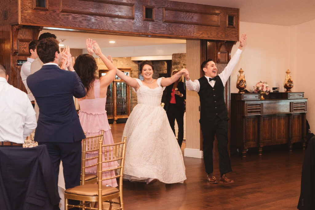 Bride and Groom make their entrance into their reception with hands up high and smiles, photographed by Philadelphia and New Jersey based travel wedding photographer, Madison Neumann Photography.