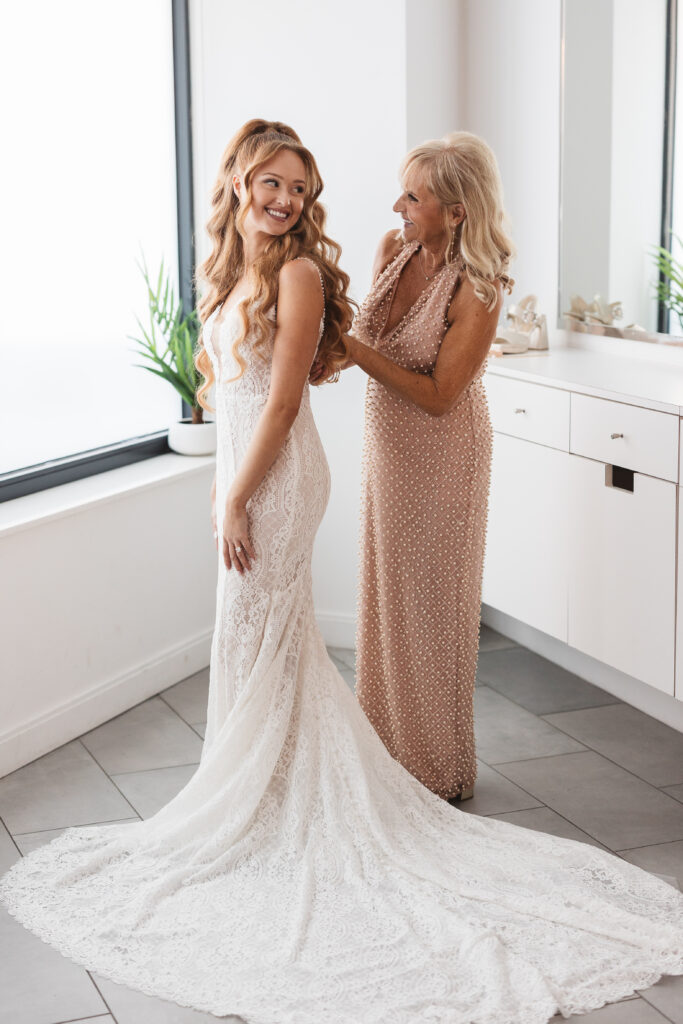 Bride getting ready with her mother as she helps her button up the back of her dress, photographed by Philadelphia and New Jersey based travel wedding photographer, Madison Neumann Photography.