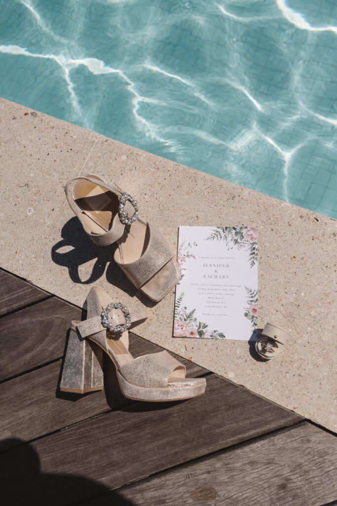 Flat lay of wedding invitation poolside with the brides shoes and ring, photographed by Philadelphia and New Jersey based travel wedding photographer, Madison Neumann Photography.