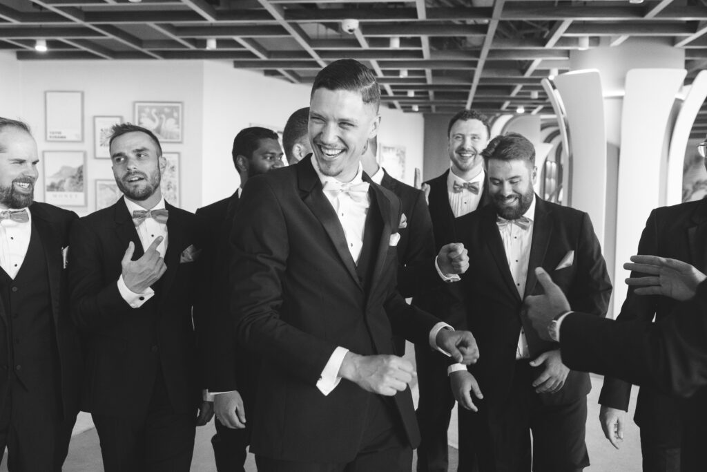 Black and white photo of groom laughing with his groomsmen, photographed by Philadelphia and New Jersey based travel wedding photographer, Madison Neumann Photography.