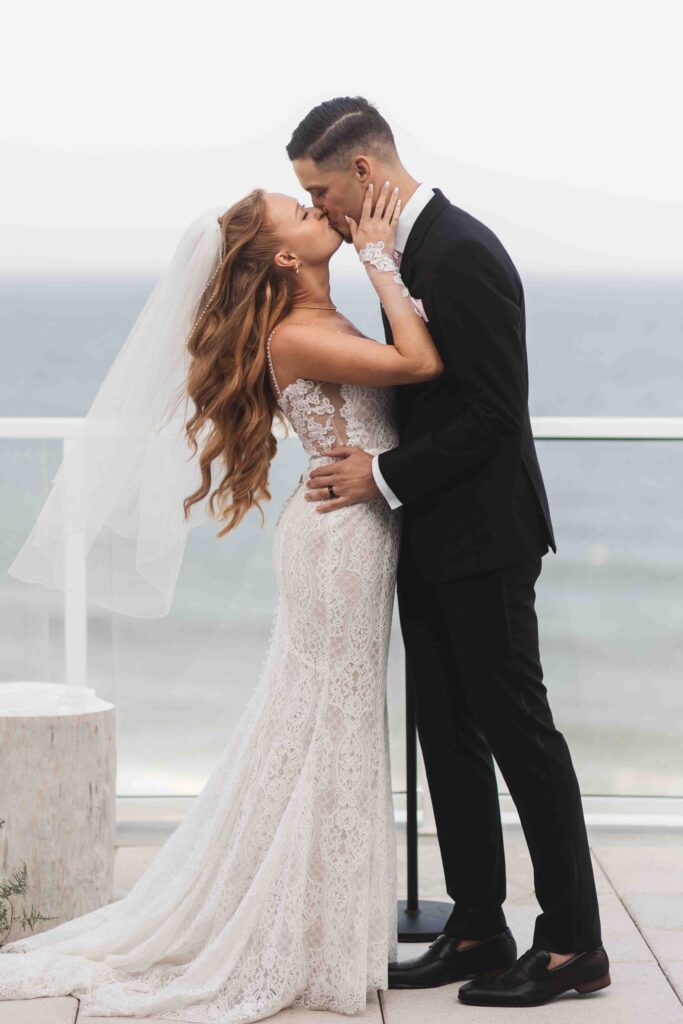 First kiss as wife and husband with the ocean in the background, photographed by Philadelphia and New Jersey based travel wedding photographer, Madison Neumann Photography.