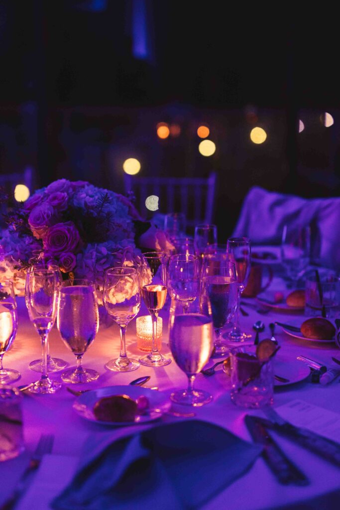 Artistic shot of the dining tables with glasses and a beautiful blue, pink, and orange lighting.