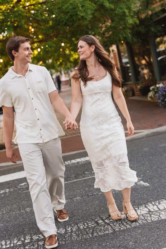 Future Mr. and Mrs. hold hands and smile at each other as they cross the street, photographed by Philadelphia and New Jersey based travel wedding photographer, Madison Neumann Photography.