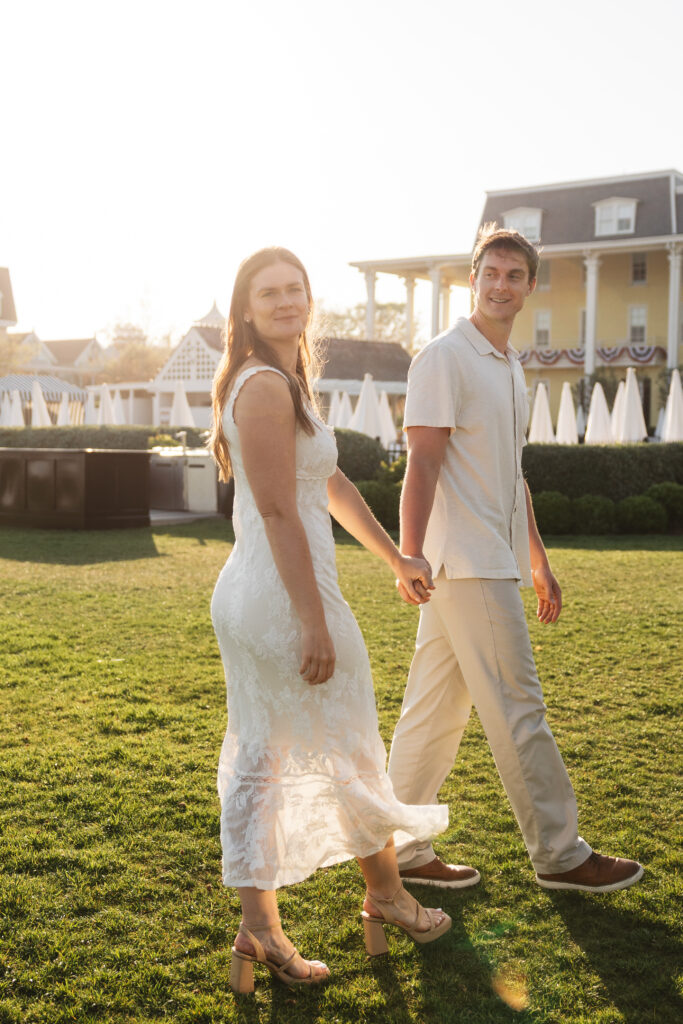 Couple walk hand in hand as the future groom leads while looking back at his fiancé as she smiles at the camera, photographed by Philadelphia and New Jersey based travel wedding photographer, Madison Neumann Photography.