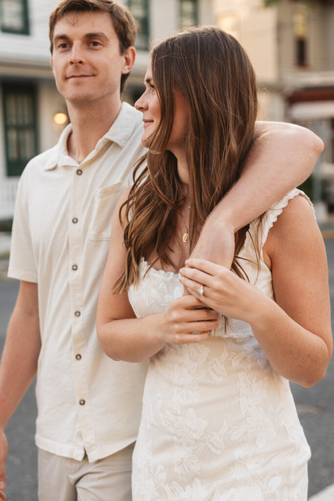 Detail shot of grooms hand around his fiancé's shoulder as she holds that hand and shows off her ring, photographed by Philadelphia and New Jersey based travel wedding photographer, Madison Neumann Photography.