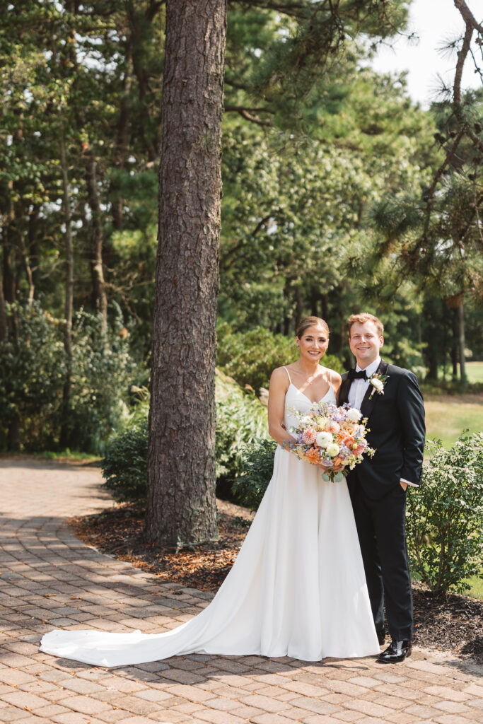 Portrait of bride and groom outside of LBI National on the stone path with trees behind them, photographed by Philadelphia and New Jersey based travel wedding photographer, Madison Neumann Photography.
