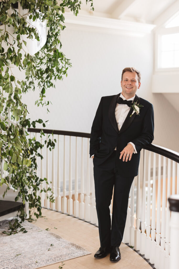 Portrait of groom leaning against the same railing and smiling at the camera, photographed by Philadelphia and New Jersey based travel wedding photographer, Madison Neumann Photography.