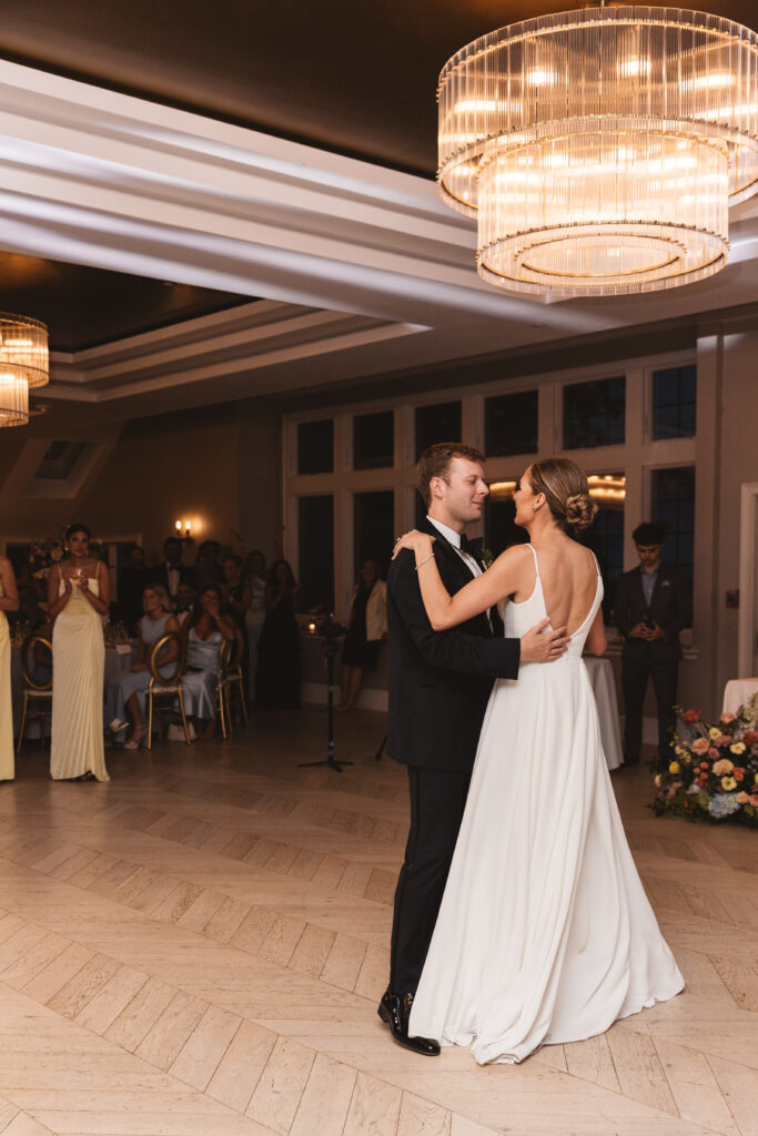 First dance as wife and husband with guests and a beautiful chandelier behind them, photographed by Philadelphia and New Jersey based travel wedding photographer, Madison Neumann Photography.