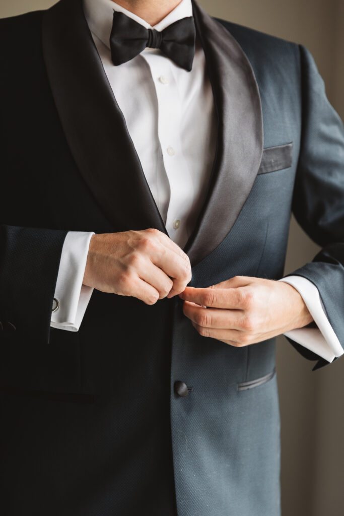 Detail shot of the groom buttoning his suit at LBI National, photographed by Philadelphia and New Jersey based travel wedding photographer, Madison Neumann Photography.